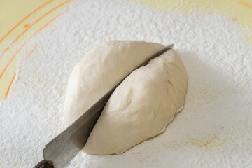 a piece of dough is cut into two parts with a knife