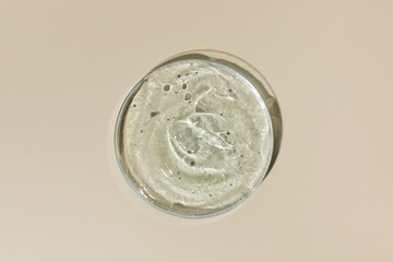 Hyaluronic acid in dish and palm leaf shadow on yellow background upper view