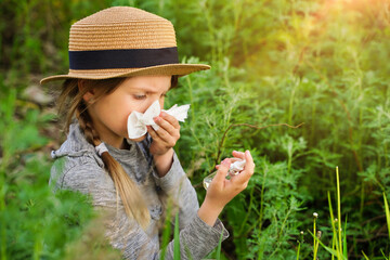 Young girl blowing nose with nasal sprays and other medication in foreground - allergy concept