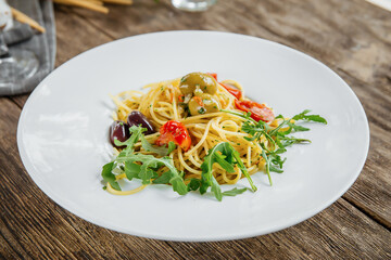 Portion of italian spaghetti pasta with olives and herbs