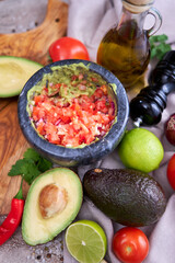 making guacamole - crushed avocado in marble mortar and ingredients