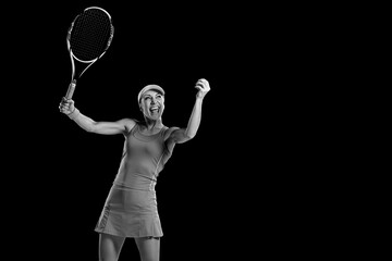 Fototapeta na wymiar Monochrome portrait of amazed smiling woman holding racket and playing tennis on black background