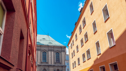 Narrow street in the old city of Nysa, Poland. Baroque church of St. Apostles Peter and Paul in the end of the street. Tenements on the both sides of the street.