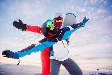 Happy couple man and woman snowboarders background sunset ski resort. Concept friends travel love...