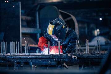 Factory industrial weld worker in workplace with spark. Professional welder erecting metal steel