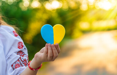 A child holds a heart of the Ukrainian flag. Selective focus.