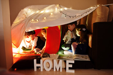 Obraz na płótnie Canvas Playing kids with kitty in tent at night home. Hygge mood.
