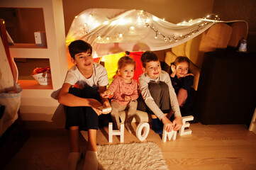 Obraz na płótnie Canvas Kids in tent waching tv at night home. Hygge mood.