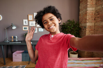 African happy kid waving his hand and smiling during video call on his mobile phone
