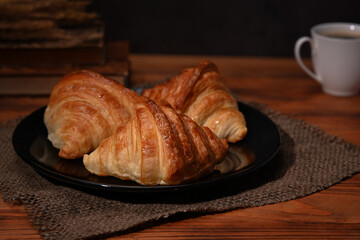 Homemade croissants with and coffee cup on wooden table. Breakfast, bread bakery products cafe concept