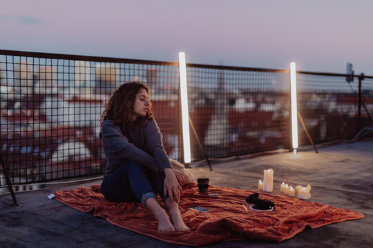 Unhappy young woman resting and sitting on the roof with city view.