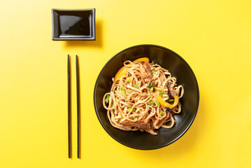 Asian udon noodles with sauce on yellow background