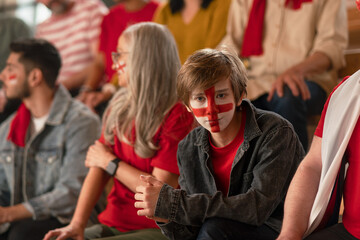 Fototapeta premium Excited football fans supporting English national team in live soccer match at stadium.