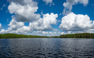 Typical landscape of Karelia. Lake, blue sky, white clouds. Forest