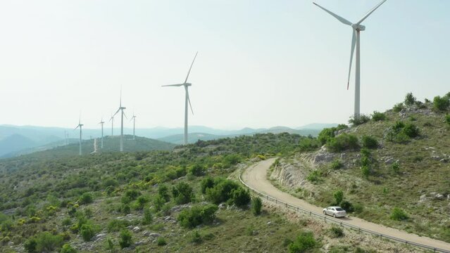 Aerial view of windmills in the mountains and car traveling. Landscape nature and a source of clean energy from the air, people and nature.