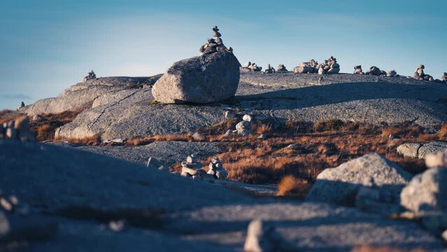 A stone garden in the stark Nordic landscape. Small stone cairns are arranged without a pattern. Slow-motion, pan right.