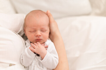 Unrecognizable mother holding her newborn son at home, close-up