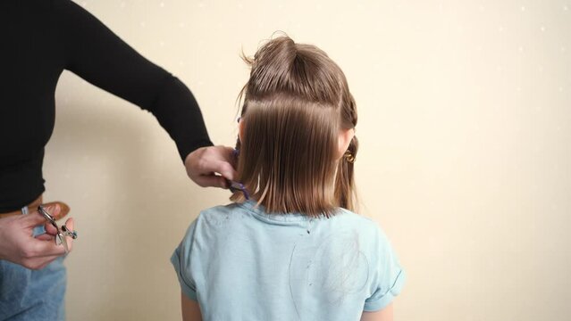 Mom combs her daughter's wet hair and cuts. cutting hair at home. life hacks and rules of hair care. special combs and scissors for hairdressers.