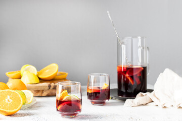 Homemade red wine sangria with orange, apple, strawberry and ice in pitcher and glass on rustic...