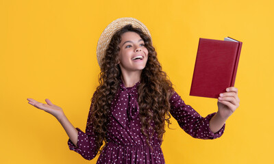 smiling child with frizz hair recite book on yellow background