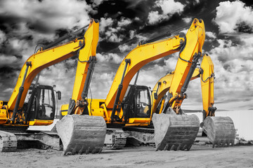 Powerful excavators at a construction site against a cloudy evening sky. earthmoving construction equipment. Lots of excavators.