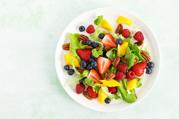 Fruit and berry salad with strawberry, blueberry, raspberry, mango and pecan nuts. Healthy food, diet. Top view