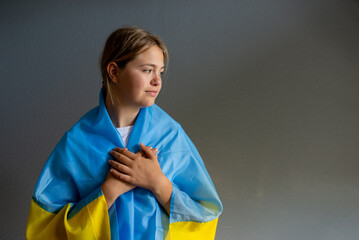 Flag of Ukraine in hands of ukrainian girl. Teenager girl lookin aside wearing blue and yellow flag...
