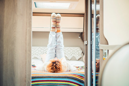 Healthy traveler woman doing stretching and workout exercises inside a campe van bedroom getting up the legs. Alternative van life off grid lifestyle people. Female laying on bed having fun