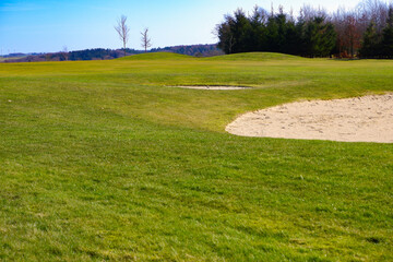 Hilly landscape. Green grass on the hills among the trees in early spring. Beautiful landscape in early springtime