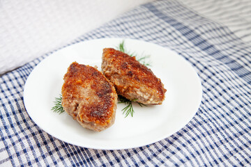 White plate with beef cutlets laying on traditional cheched kitchen towel