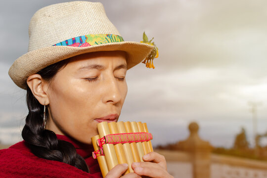 Closed shot of Latin American indigenous woman with hat playing the zampo&ntilde;a with her eyes closed