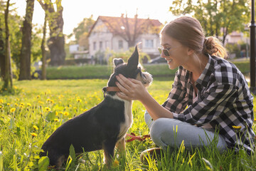 Teenage girl with her cute dog resting on green grass in park