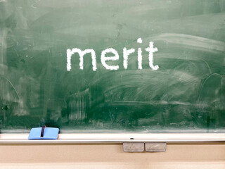 黒板にmeritの文字と黒板消しと白チョーク_正面