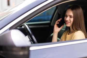 young woman driving car and talking on cell phone concentrating on the road