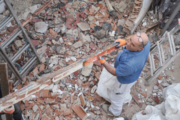 Mature worker removing old metal beams in a construction house.