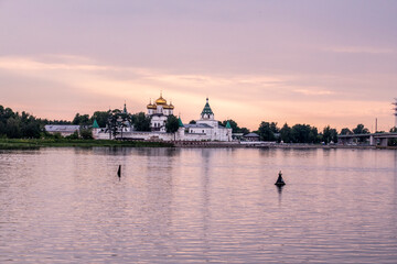 Obraz premium summer landscape with ancient churches against the backdrop of a forest and a river at sunset
