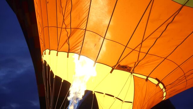 close up of a giant flame going into a hot air balloon with someone assisting in slow motion