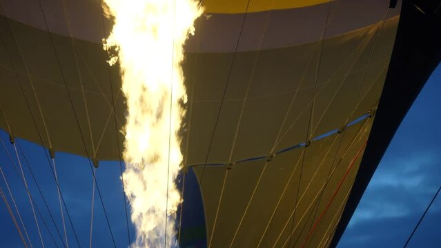close up of a giant flame going into a hot air balloon with someone assisting in slow motion