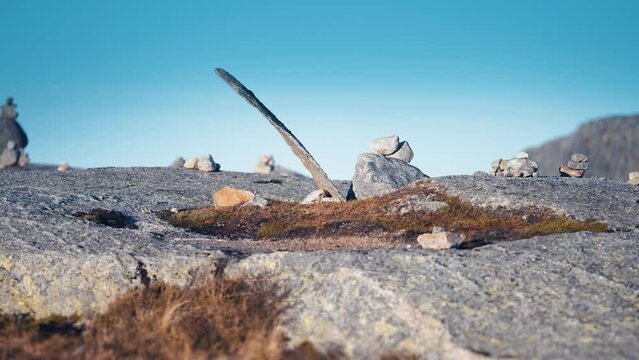 A stone garden in the stark Nordic landscape. Small stones are arranged in different shapes. Moss, lichen, and withered grass cover the stones. Slow-motion, pan right.