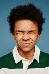 Vertical close up portrait of black teenage boy facing camera with eyes closed and funny expression