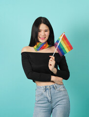 LGBTQ woman holding pride flag standing against a blue green background. Asian LGBTQ woman with rainbow scarf on neck. look smart bright and energetic cheerful. LGBTQ diversity pride concept.