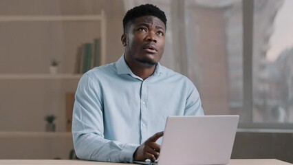 Excited african man smiling american guy works on computer does daily task deeps in thoughts thinks of problem solution makes decision recollect memory comes up with best idea finds answer create plan