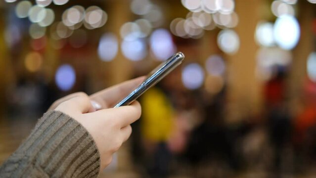 Shopping center. Moll. Finger of woman touching scroll page app on mobile phone. Browsing movie video in the internet library to watch film online.