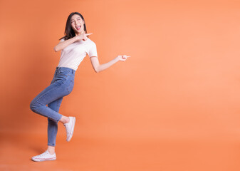 Fototapeta na wymiar Full length image of young Asian woman posing on orange background