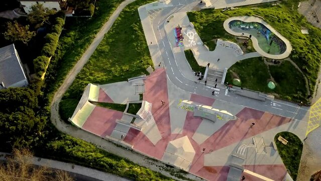 vertical drone shot of the Skatepark Parque das Gerações in Cascais Portugal. takes overhead where we can see the skate park with a lot of people skating the ramps and enjoying a wonderful sunset