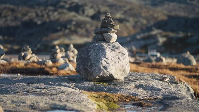 Small stone cairns scattered through the stark northern landscape. Moss, lichen, and withered grass cover the stones. Slow-motion, pan right.