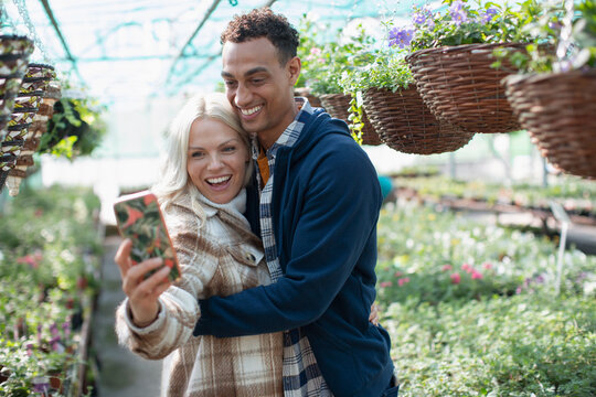 Happy couple taking selfie in garden shop