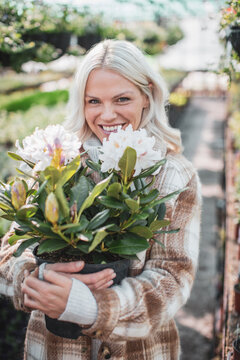Portrait happy woman holding potted flower