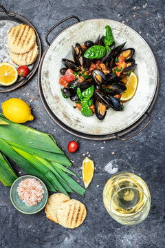 Delicious seafood mussels in sauce with glass of white wine Lemon and baguette. Clams in the shells. Fine dining in a seafood restaurant. vertical image. top view. place for text