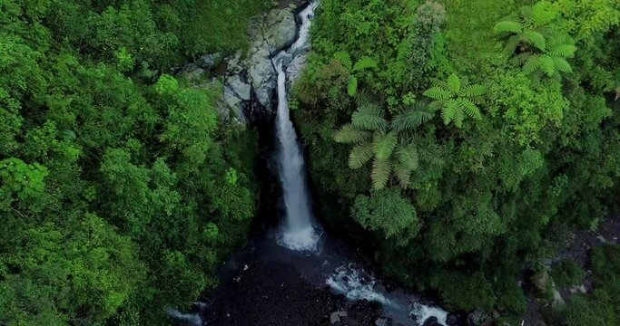 Aerial view from drone flying over nature view of waterfall with rocky river and surrounding vegetation. nature is still beautiful named Kedung Kayang Waterfall  in Central Java, Indonesia